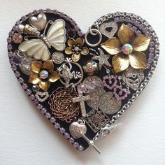 a heart shaped brooch with many different things on it's side, including flowers and butterflies