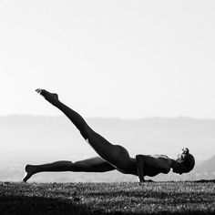 a woman is doing yoga on the grass