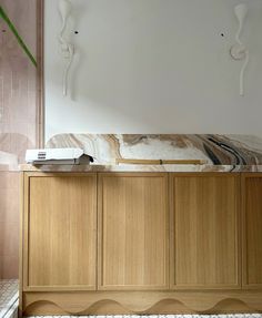 a large wooden cabinet with marble top in a living room next to a white wall