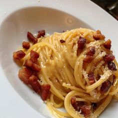 a white plate topped with spaghetti and bacon