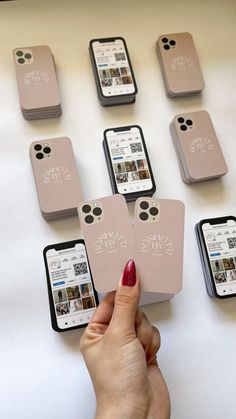 a person is holding their cell phone in front of several different phones on the table