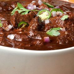 a white bowl filled with meat and vegetables