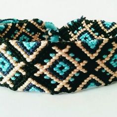 a close up of a bracelet on a white surface with blue and brown squares in the middle