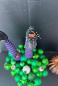 a spider sitting on top of a green ball surrounded by other balls and decorations in front of a gray wall