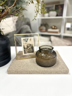 a glass vase sitting on top of a white table next to a small potted plant