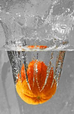 an orange floating in the water with its top half submerged