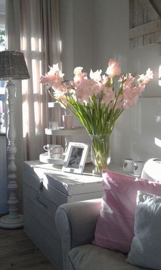 a vase filled with pink flowers sitting on top of a white dresser next to a window