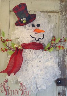 a snowman door hanger with a red scarf and hat on it's head