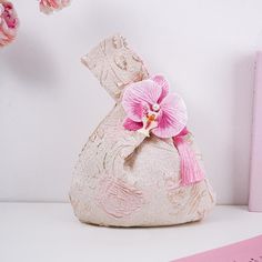 a pink flower sitting on top of a white vase next to a pink bookcase