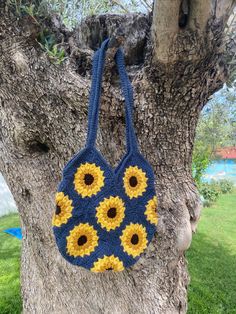 a crocheted sunflower purse hanging from a tree