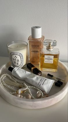 an assortment of perfumes on a tray next to a candle