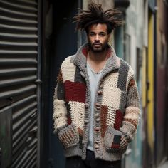 a man with dreadlocks standing in an alleyway wearing a multicolored jacket