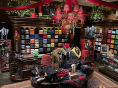 a room filled with lots of different types of clothing and hats on display in front of a chandelier