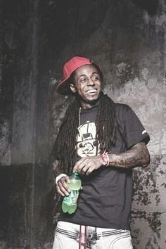 a man with dreadlocks and a red hat holding a green bottle in his right hand