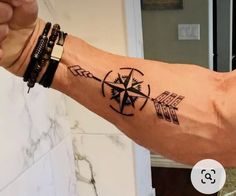 a man's arm with an arrow and compass tattoo on the left side of his arm