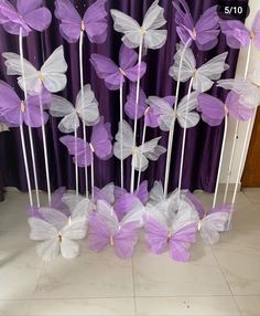 purple and white butterflies on sticks in front of a curtain