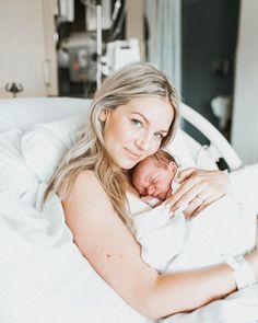 a woman laying in bed holding a baby