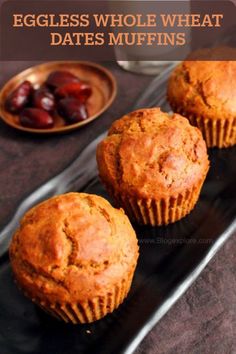 three muffins on a black plate next to a glass of milk and some cherries