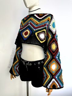 a mannequin wearing a colorful crochet sweater on display in front of a white wall