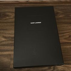 the saint laurent book sits on top of a wooden table