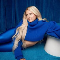 a woman with long blonde hair is laying on the floor wearing blue clothing and posing for a photo