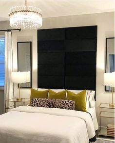 a bedroom with a white bed, black headboard and two mirrors on the wall