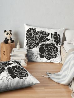 two black and white pillows sitting on top of a wooden floor next to a stuffed panda bear