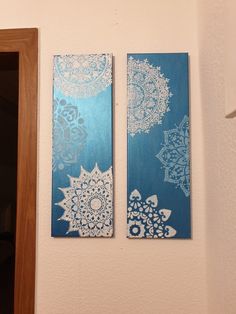 two blue and white paintings hanging on the wall next to a door in a bathroom