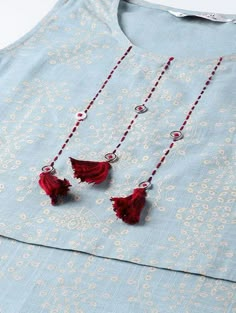 two red tasselled necklaces hanging from a blue shirt