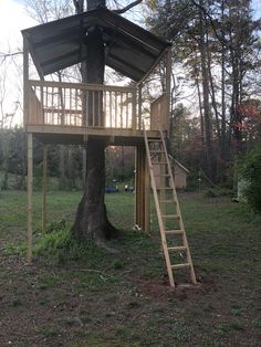 a tree house built into the side of a tree in a field with stairs leading up to it