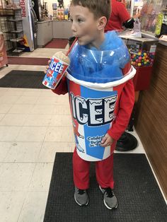 a young boy is dressed up as a bucket and holding a drink in his hands