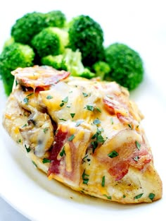 a white plate topped with chicken covered in cheese and bacon next to broccoli