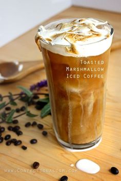 iced coffee with marshmallow ice cream in it on a wooden table next to beans