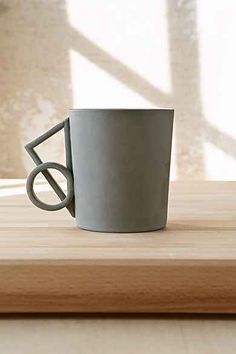 a gray coffee cup sitting on top of a wooden table