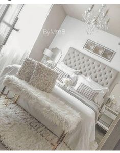 a bedroom with white furniture and chandelier