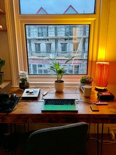 a desk in front of a window with a laptop on it and a lamp next to it