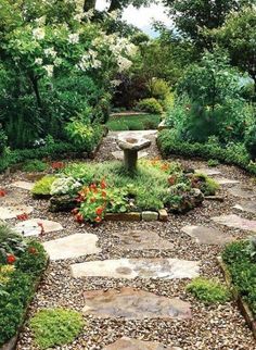 a garden with lots of plants and flowers on it's sides, including a stone bench in the middle