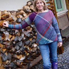 a woman standing in front of a pile of firewood with her hands on the logs