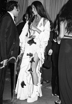 black and white photograph of a woman in a long dress standing next to two men