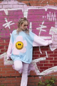 The Happy Flower Jumper! A Blue bodice complete with large Pink Fleece Flower and Yellow Chenille Smiley Face for the centre. Hand sewn on with playful thick thread. Pink Sleeves!! What a great addition to your weird and wonderful Wardrobe. Bringing lots of happy happy vibes! Very 90s!  STYLING TIPS: Looks great matched with Denim Jeans and Trainers. Have the coolest hangover Sweatshirt at a Festival or chuck it on down at the beach. So many fun styling options with this one.  SIZING GUIDE: Can 90s Pastel Fashion, Playful Spring Sweatshirt For Loungewear, Playful Spring Loungewear Sweatshirt, Playful Blue Sweatshirt For Spring, Cute Oversized Blue Tops, Light Blue Sweatshirt For Spring Loungewear, Blue Oversized Sweatshirt For Spring, Oversized Blue Sweatshirt For Spring, Cute Blue Sweatshirt With Relaxed Fit