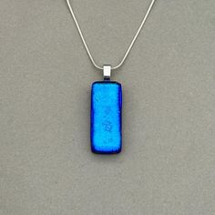 Blue Dichroic fused glass Necklace with dark blue shift. Handmade in West Yorkshire. Please note this listing is for the necklace only. Matching earrings available here; All pendants are handmade and unique, therefore patterns and colours may differ from the images shown. Dichroic glass has a transmitted colour and a completely different reflective colour; these two colours shift depending on the angle of view. This pendant has a Silver Plated glue on bail with the choice of different Sterling S Minimalist Blue Necklace With Rectangular Pendant, Modern Blue Necklaces As A Gift, Modern Blue Jewelry With Rectangular Stone, Modern Blue Rectangular Jewelry, Blue Minimalist Rectangular Pendant Jewelry, Modern Blue Rectangular Necklace, Modern Rectangular Glass Jewelry, Blue Necklaces With Rectangular Stone For Gift, Blue Square Necklace Perfect For Gifts