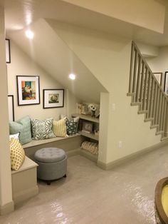 a living room filled with lots of furniture and pictures on the wall next to stairs