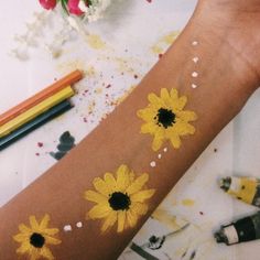 a person's arm with sunflowers painted on it and crayons