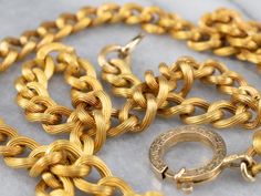 Another stunning Victorian-era piece! This antique chain necklace is crafted of 18 karat yellow gold in the distinctive style of the early 1900's Victorian era. Each of the links is grooved, with rope twist details, finished with an oversized engraved clasp. The workmanship is exquisite, and the condition is excellent, especially considering the great age of the necklace. Metal: 18K Yellow Gold Width of Chain: 7.7 mm Length of Chain: 21 Inches To view a video of this piece check out the link bel Luxury Antique Link Chain Necklace, Formal Gold Rope Chain Link Necklace, Elegant Yellow Gold Rope Chain Necklace With Curb Detail, Elegant Yellow Gold Curb Chain Necklace, Antique Gold Engraved Chain Necklace, Victorian Necklace With Oval Link Curb Chain, Victorian Gold Necklace With Figaro Chain, Vintage Yellow Gold Curb Chain Necklace, Victorian Wheat Chain Necklace For Formal Occasions