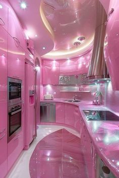 a pink kitchen with stainless steel appliances and counter tops is lit up by lights on the ceiling