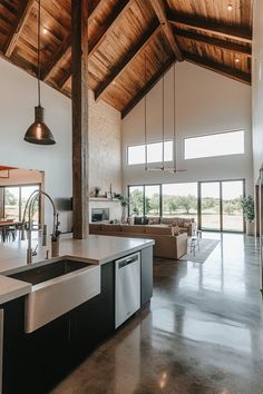 an open kitchen and living room area in a house with exposed wood ceilinging, large windows