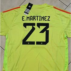 the back of a yellow soccer jersey with black and white stripes on it, which reads e martinez