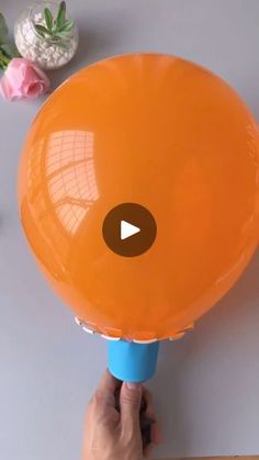 a person holding an orange frisbee on top of a white table next to flowers