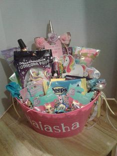 a pink basket filled with lots of toys and snacks on top of a wooden table