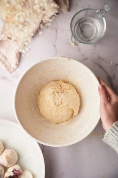 a person holding a doughnut in a bowl next to some other food on plates